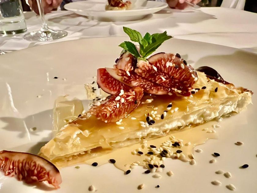A slice of crisp filo with honey, black and white sesame, fresh figs and mint, on a white cloth